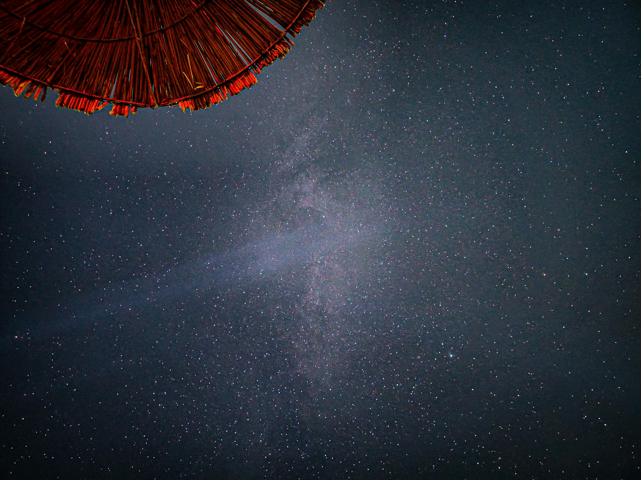 View of the Milky Way from Himarë, Albania, with a silhouetted parasol.