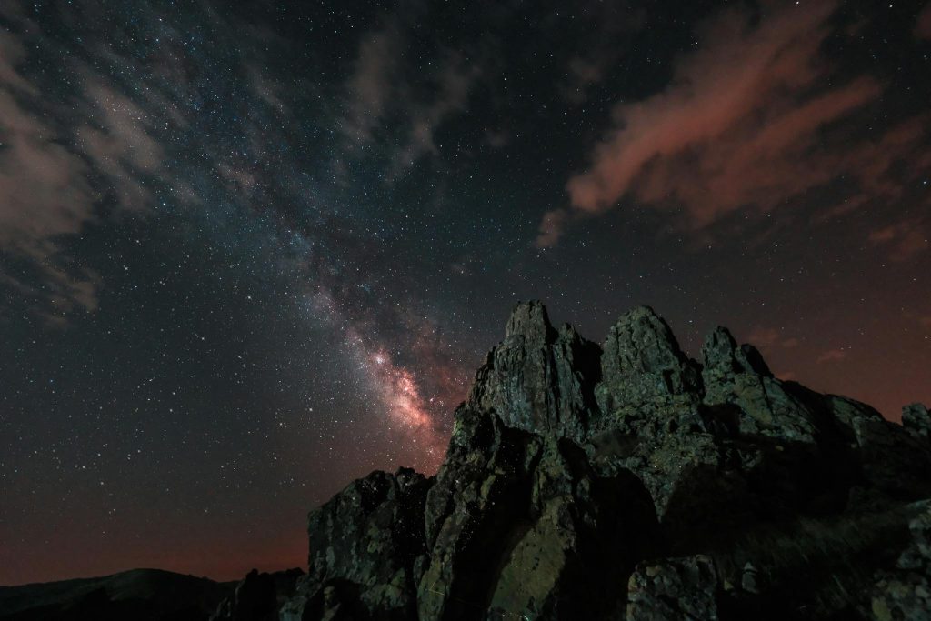 A breathtaking view of the Milky Way over sharp mountain peaks under a vibrant starry night sky.